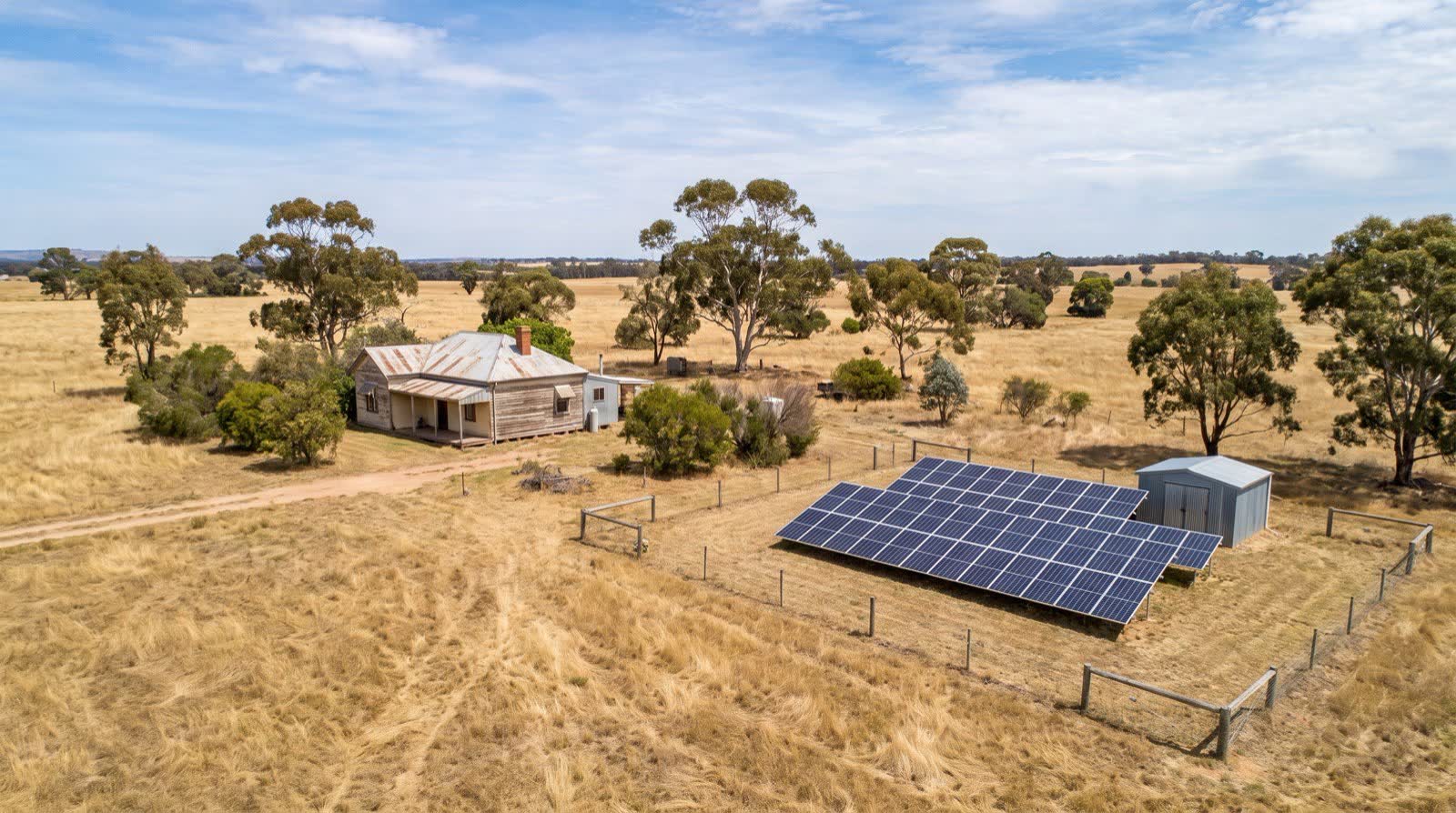 Remote off-grid farmhouse in regional Victoria with a ground-mounted solar array and battery shed, no power lines in sight