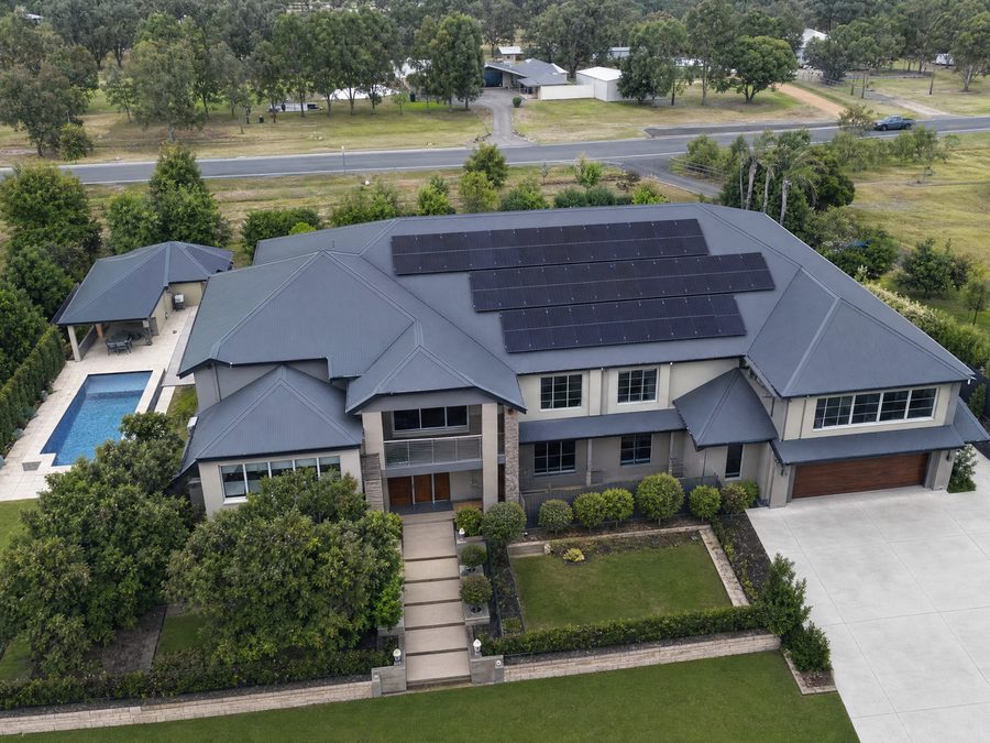 A large rooftop array on a two-storey home with a pool