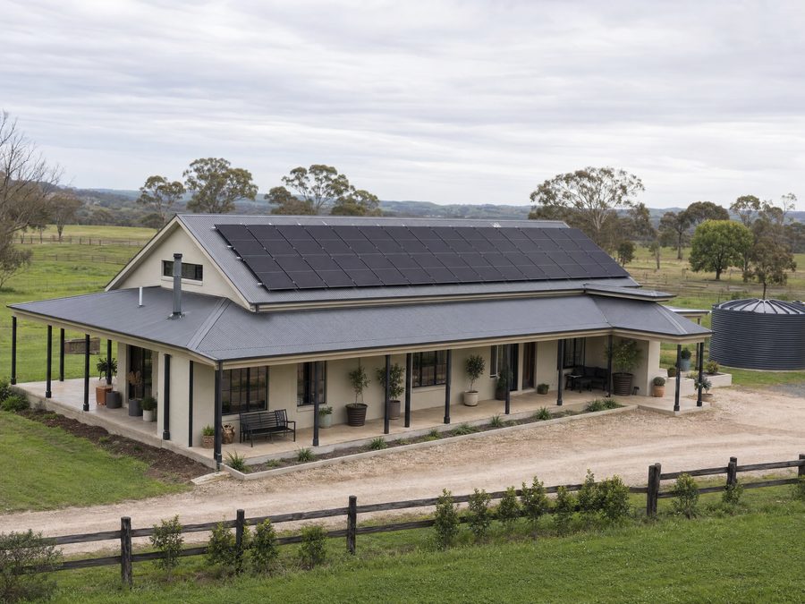 Solar panels across the roof of a rural homestead with paddocks behind
